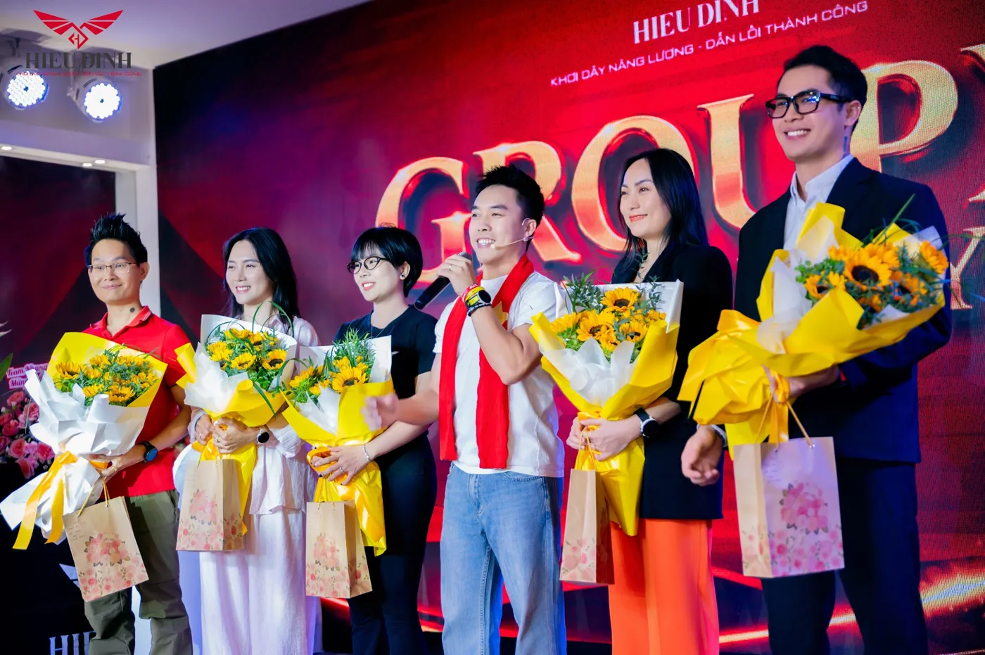 Vinh danh học viên trên sân khấu, tay cầm hoa